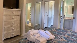 A bedroom with a bed, a dresser, a television, and a bathroom visible through an open door.