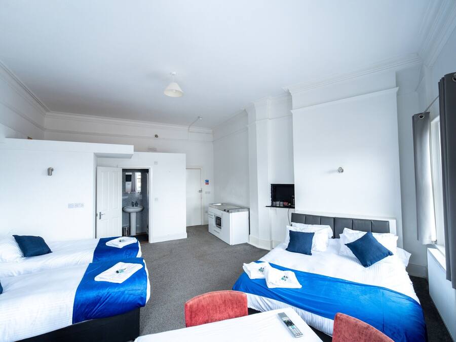 A hotel room with two beds, a desk, a chair, a TV, and a window.
