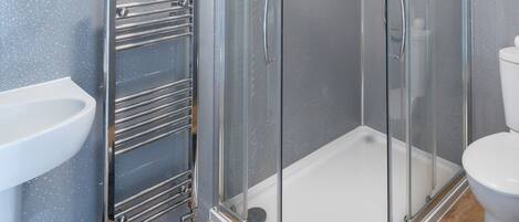Un baño moderno con cabina de ducha de vidrio, un lavamanos blanco y un inodoro.