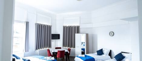A hotel room with two beds, a desk, a chair, a TV, and a wardrobe.