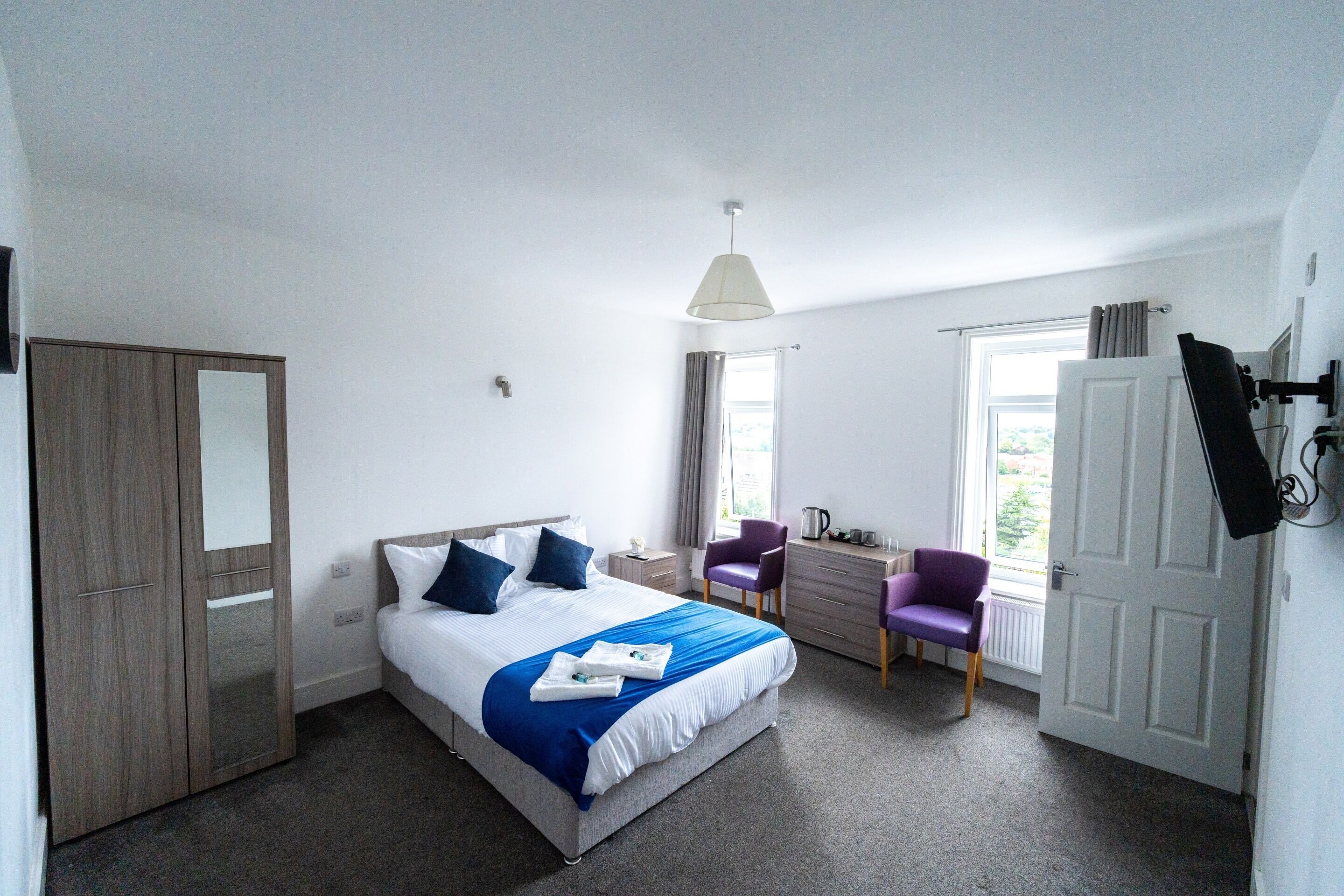 Ein Schlafzimmer mit Bett, Schreibtisch, Stuhl, Kleiderschrank und Fernseher.