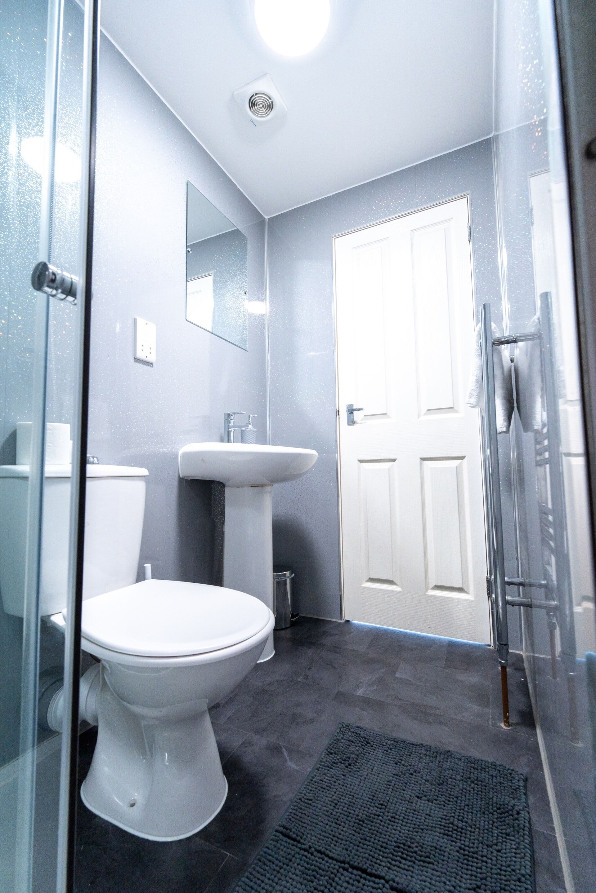 A bathroom with a toilet, sink, and glass shower enclosure.