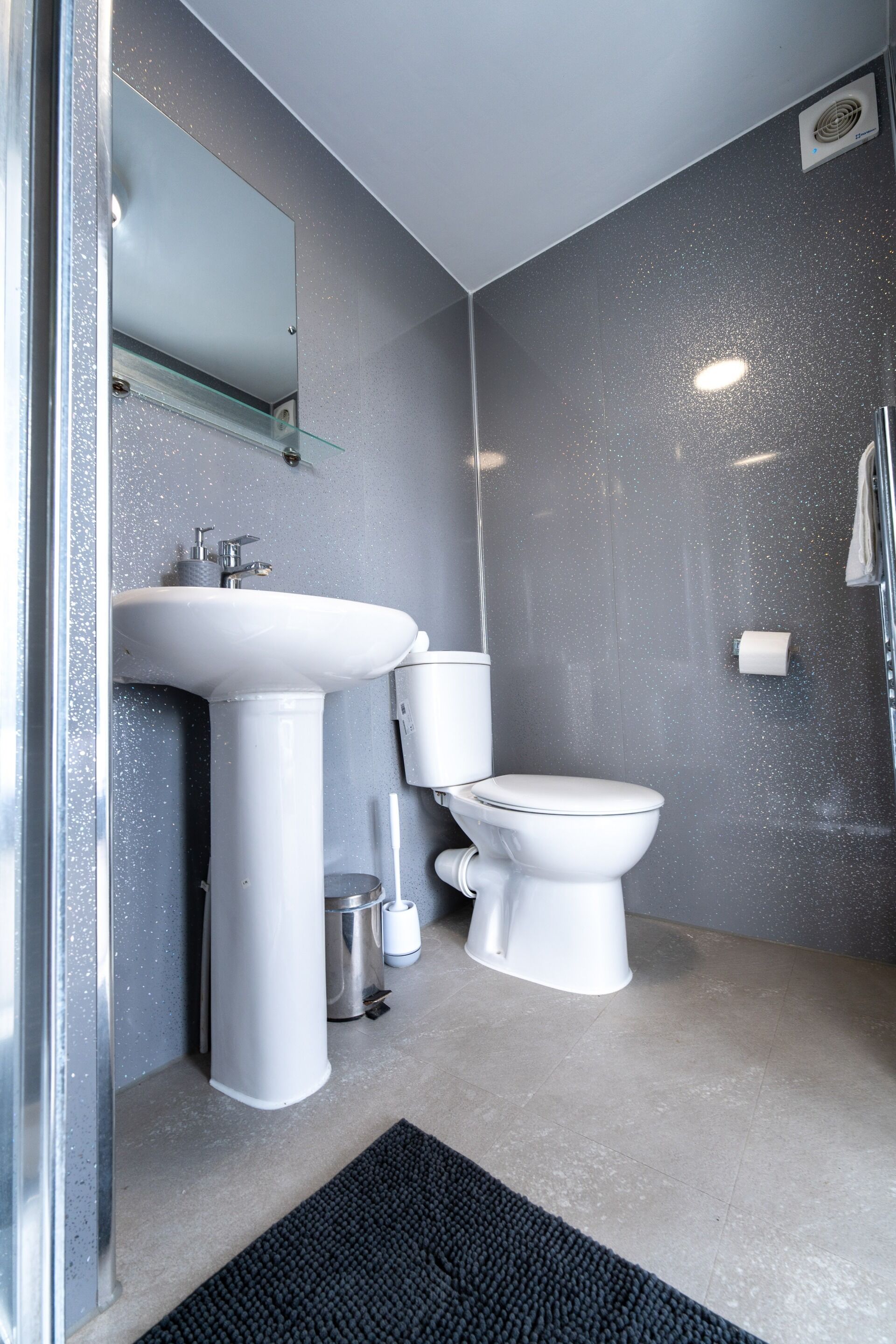Un baño moderno con lavamanos, inodoro y espejo blancos.