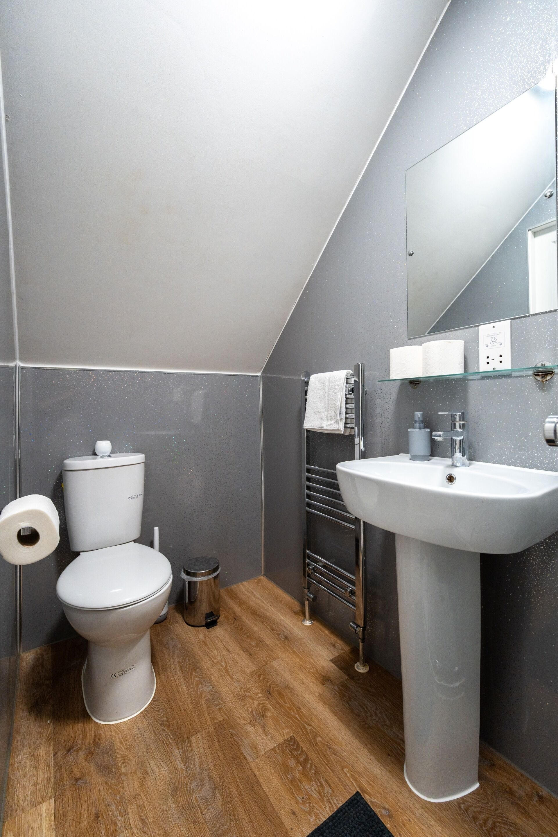 A modern bathroom with a toilet, sink, mirror, and towel rack.