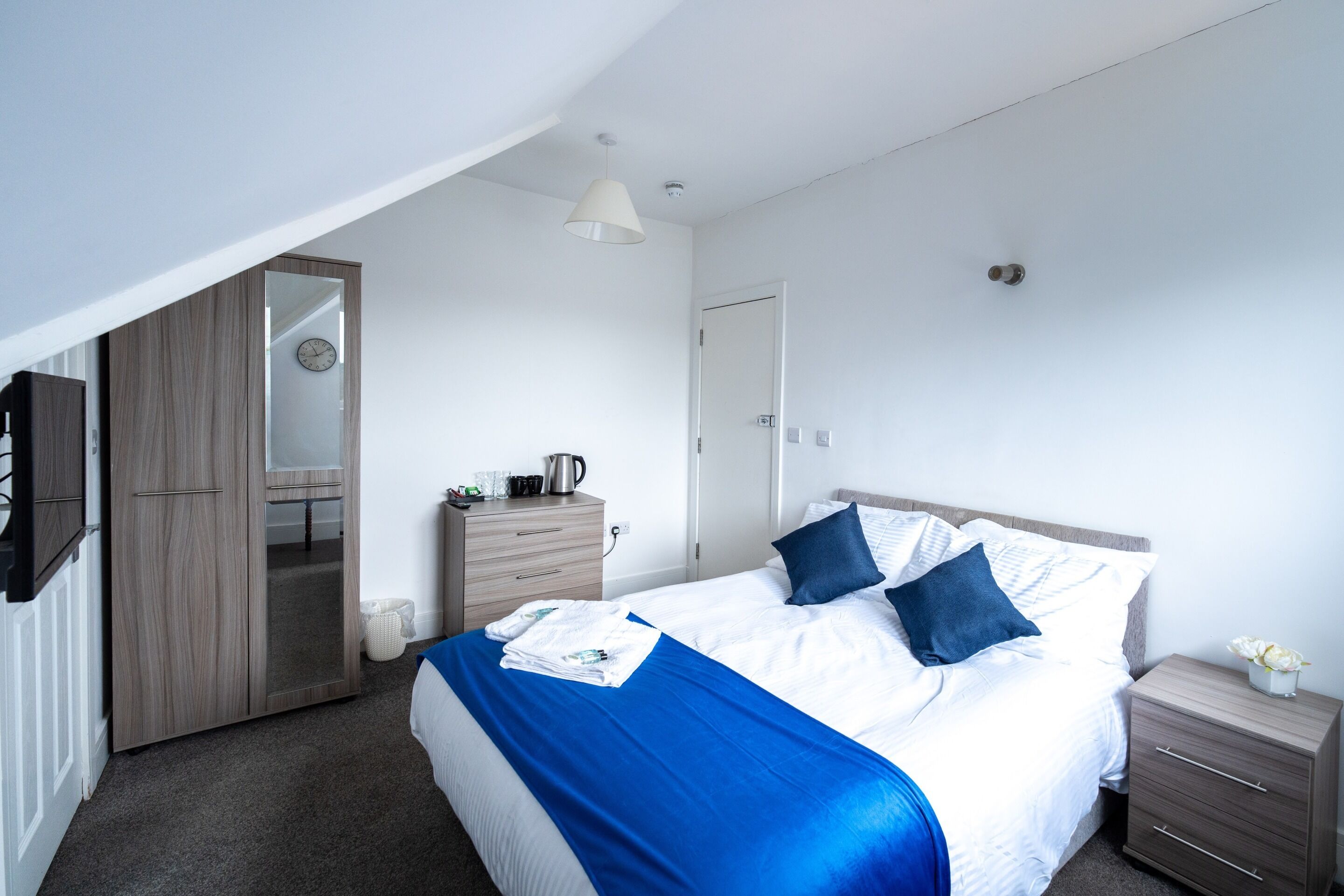 Une chambre à coucher comprenant un lit, une table de chevet, une commode, un miroir et un luminaire au plafond.