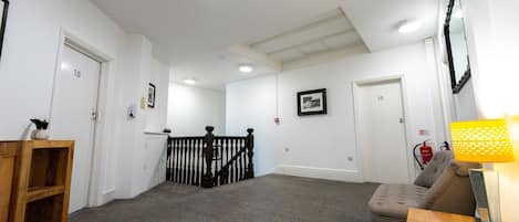 A hallway with carpeted floors, a staircase with a wooden railing, and a door marked with the number 10.