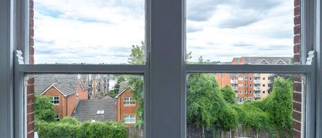 A window with a view of a residential street, houses, and a parked car.