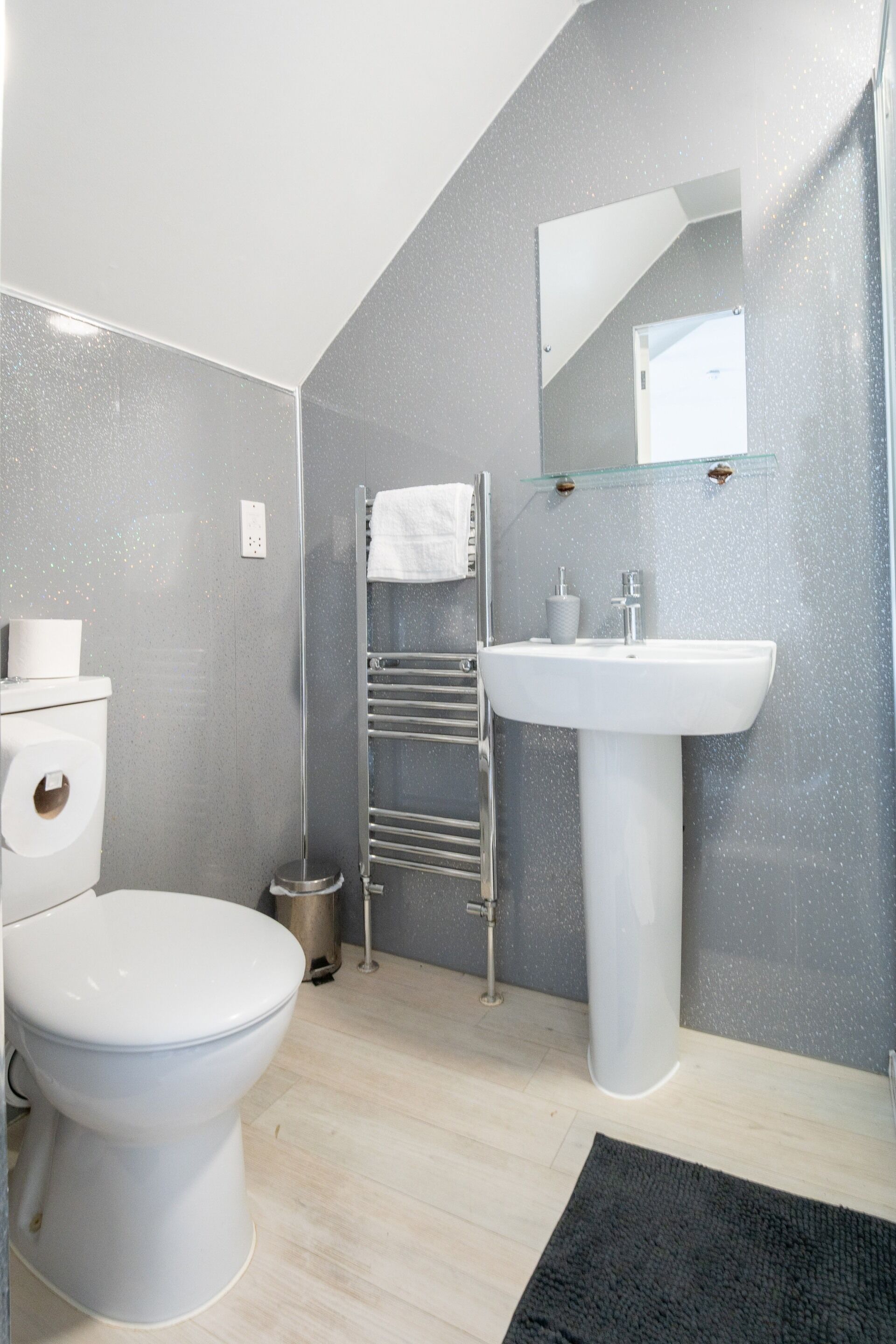 A modern bathroom with a toilet, sink, towel rack, and a mirror.