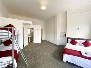 Quarto de hotel com beliches, uma cama de casal e um closet espaçoso.