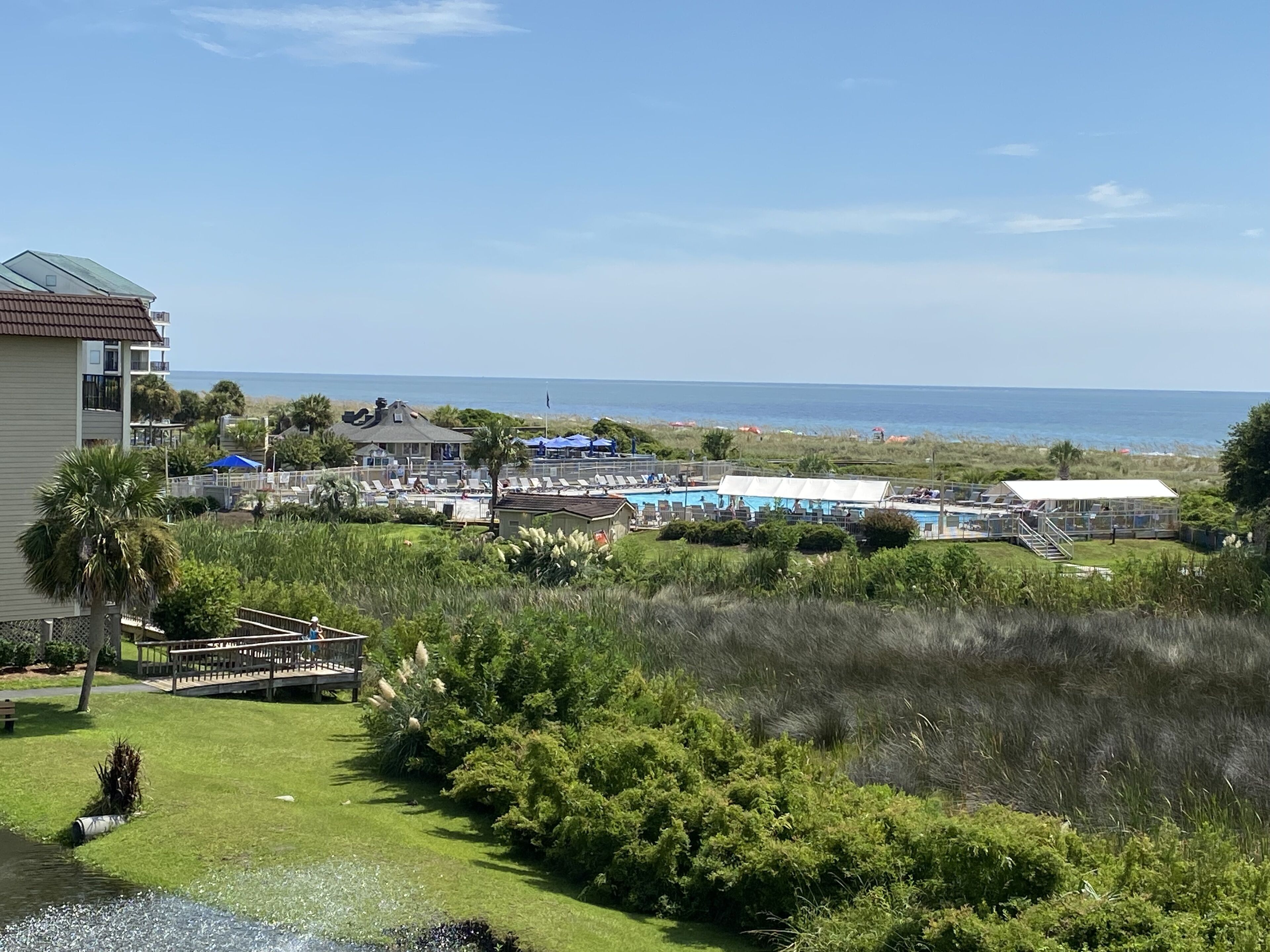 Ein Resort mit Poolbereich, Blick auf den Strand und einer grünen Landschaft.