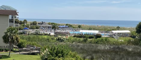 Ein Resort mit Poolbereich, Blick auf den Strand und einer grünen Landschaft.