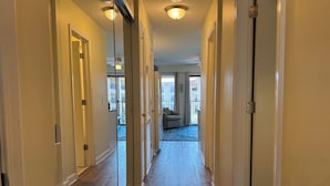 A hallway with wooden flooring, white walls, and a ceiling light fixture.