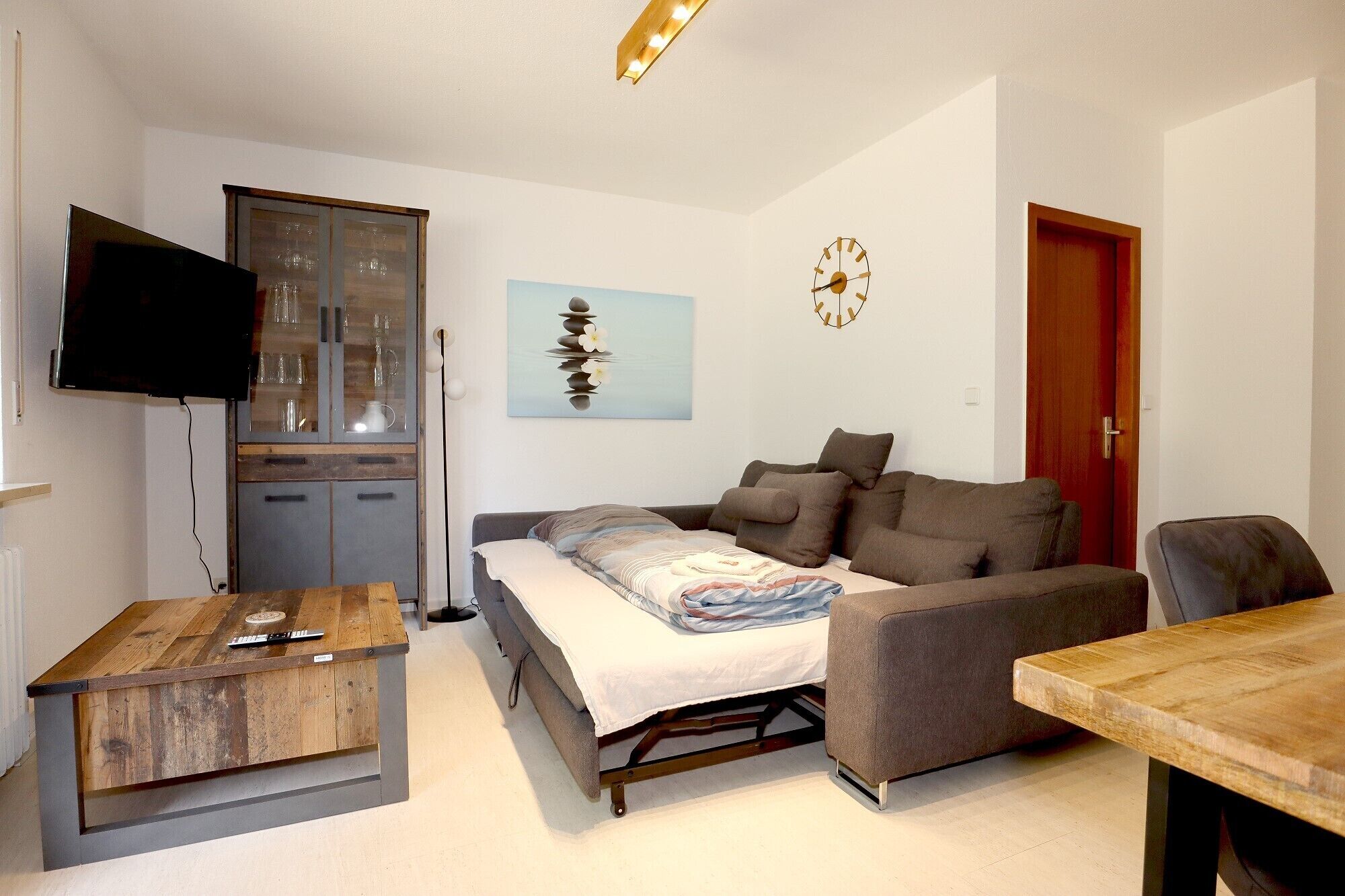 A compact living space with a sofa, a small table, a television, and a cabinet.