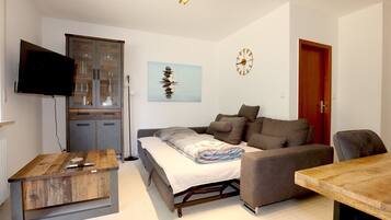 A compact living space with a sofa, a small table, a television, and a cabinet.