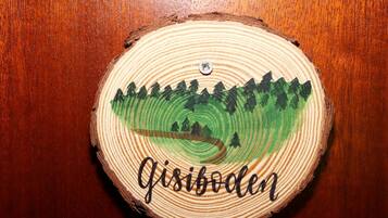 A wooden coaster with a painted landscape and the word 'Gisibolen' on it.