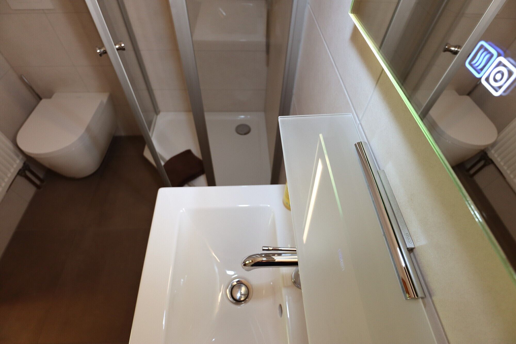 Une salle de bain moderne avec un lavabo blanc, un robinet chromé et une douche à parois de verre.