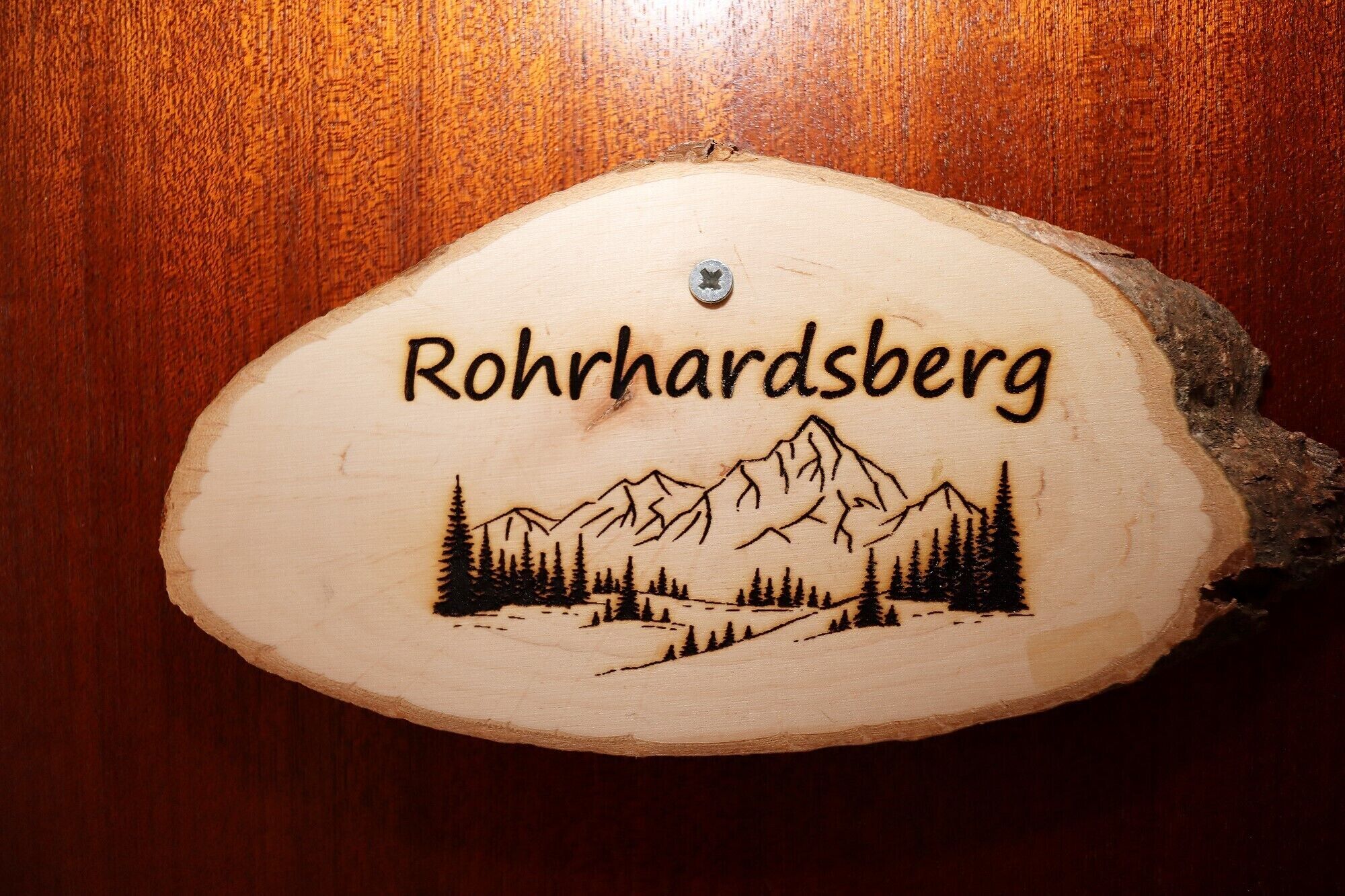 En træplade med navnet 'Rohrhardsberg' og en udskæring af et bjerglandskab.