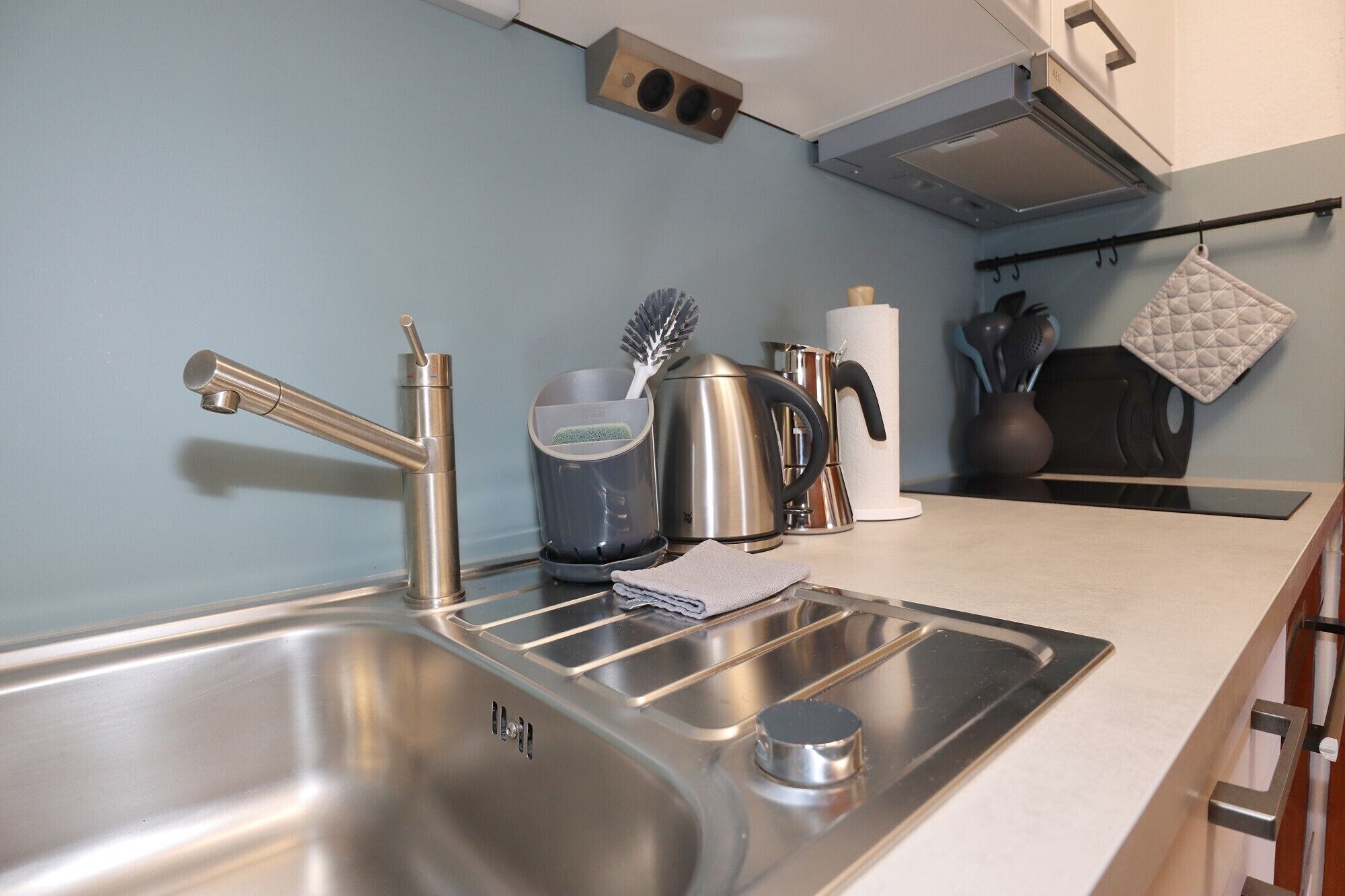 Een moderne keuken met roestvrijstalen apparatuur, een waterkoker, een koffiezetapparaat en een waterkokerborstel.