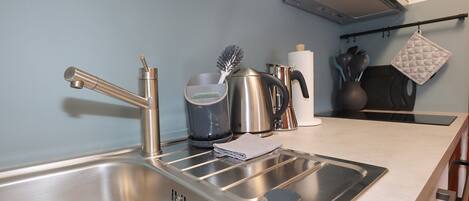 Een moderne keuken met roestvrijstalen apparatuur, een waterkoker, een koffiezetapparaat en een waterkokerborstel.