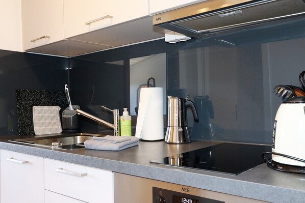 A modern kitchen with a built-in stove, a coffee maker, and a kettle. - Carpediem Apartments (Schoenwald)