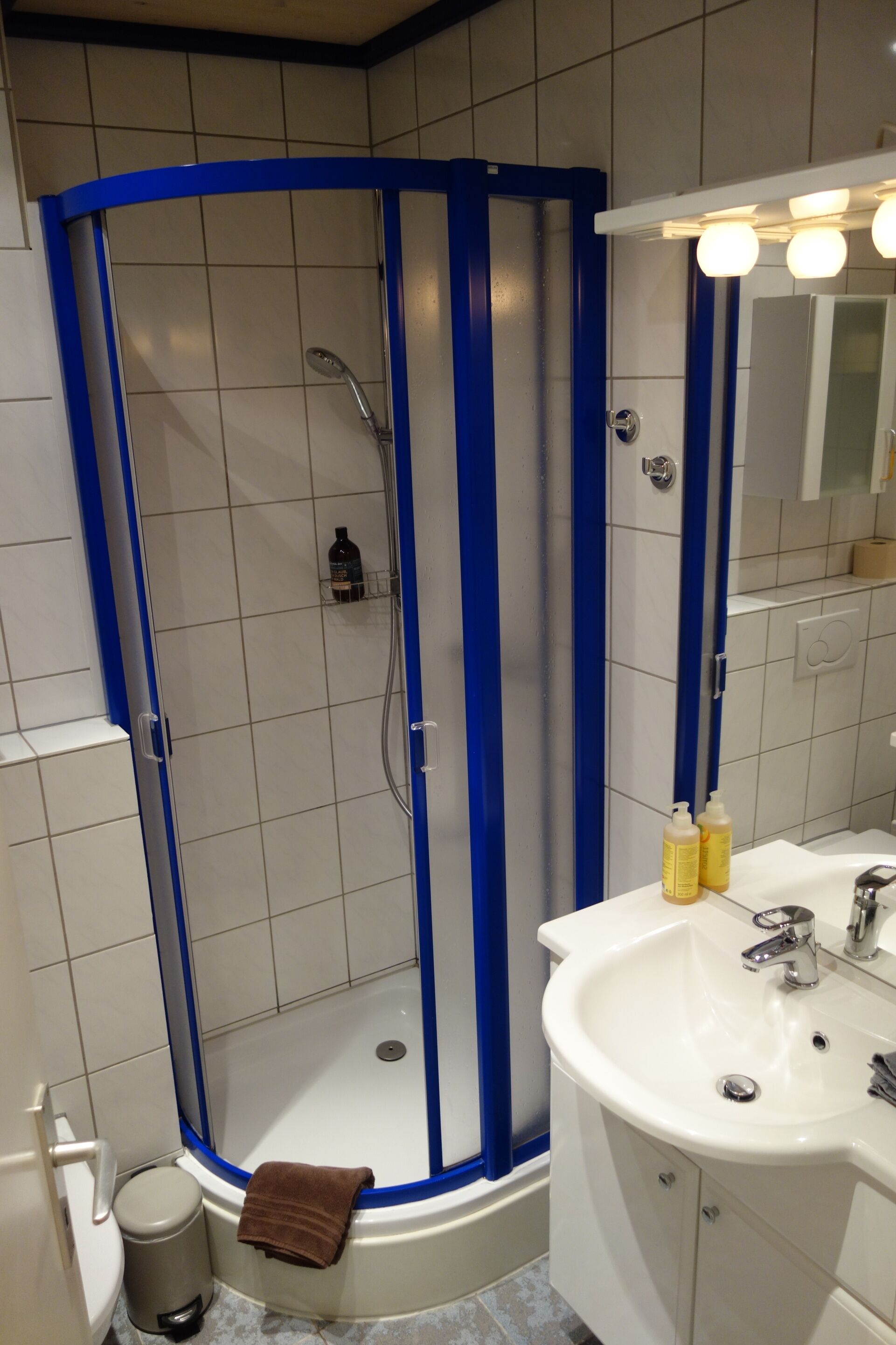 Een moderne badkamer met een glazen douchecabine, een wit wastafelmeubel en een spiegel erboven.