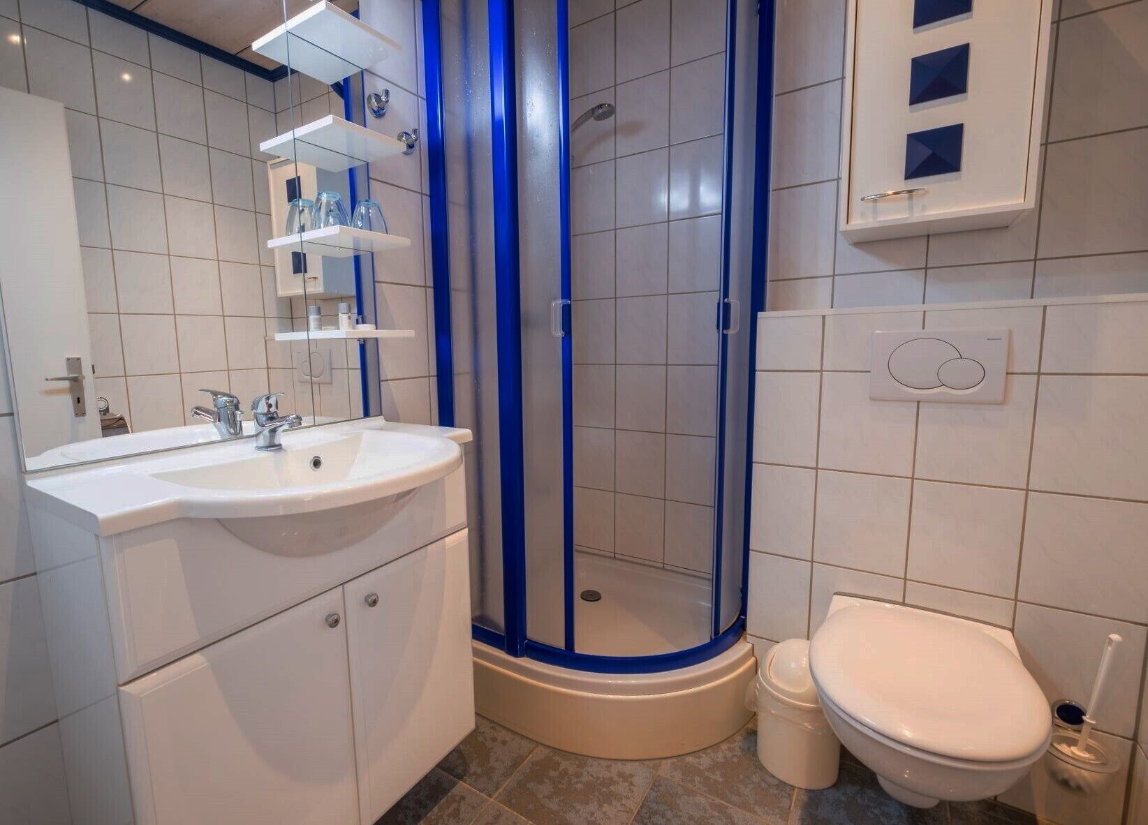 Casa de banho com lavatório branco, sanita e cabine de duche.