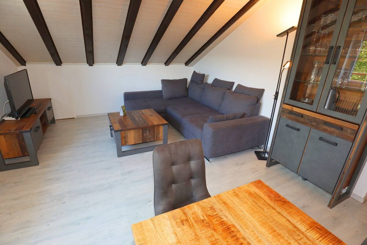 A modern living room with a sectional sofa, a wooden coffee table, a TV stand, and a cabinet with glass doors.