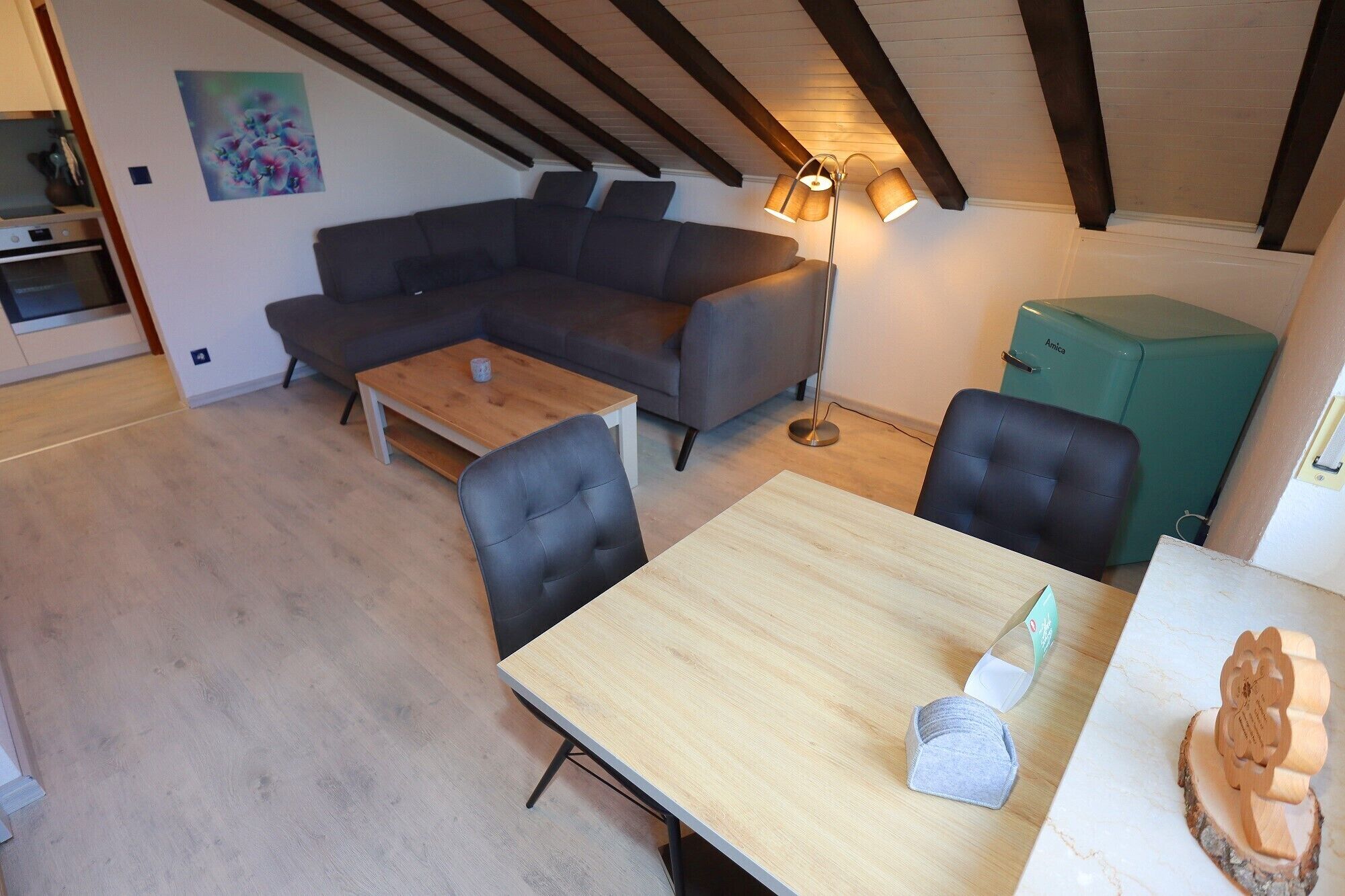 A modern living space with a wooden dining table, a gray sofa, and a floor lamp.