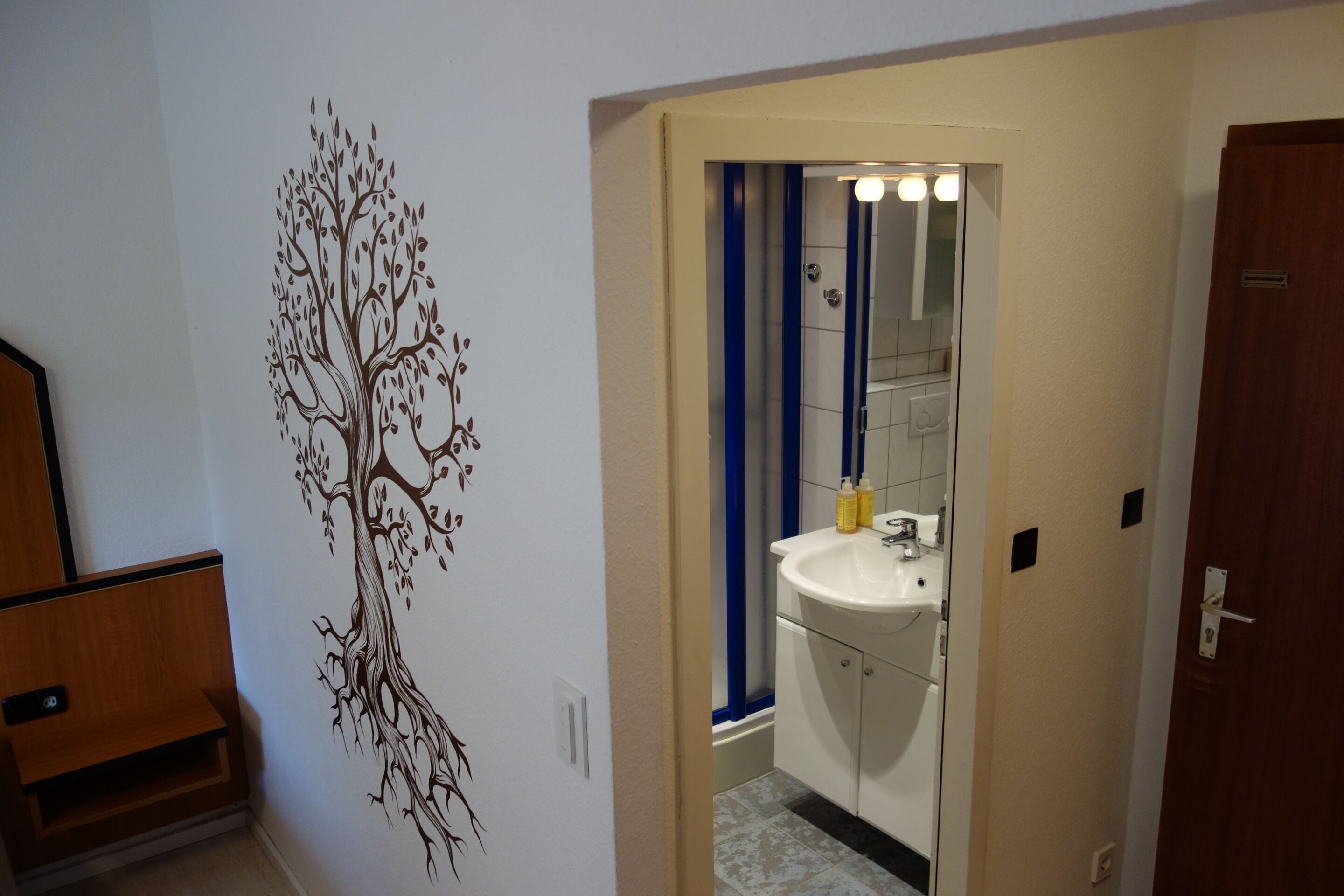 A bathroom with a tree decal on the wall, a sink, and a mirror.