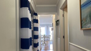 A hallway with a striped curtain, a dining area with a table and chairs, and a painting on the wall. - Ocean Front - Ocean Villas B329-Professionally Managed by HHIB&T Vacation Rentals (Hilton Head Island)
