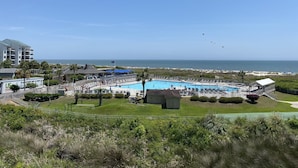Un complexe hôtelier doté d’une piscine, offrant une vue sur la plage et arborant un panneau indiquant qu’il propose des plats américains.