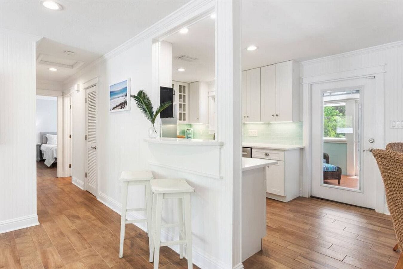 A modern kitchen with white cabinetry, a countertop, and a small island with stools.