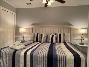Ein Schlafzimmer mit einem großen Bett, zwei Nachttischlampen, einem Deckenventilator und einem Kleiderschrank.