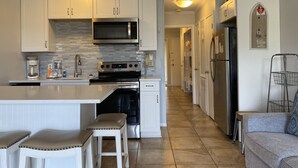 A modern kitchen with white cabinetry, a stainless steel refrigerator, and a built-in oven.
