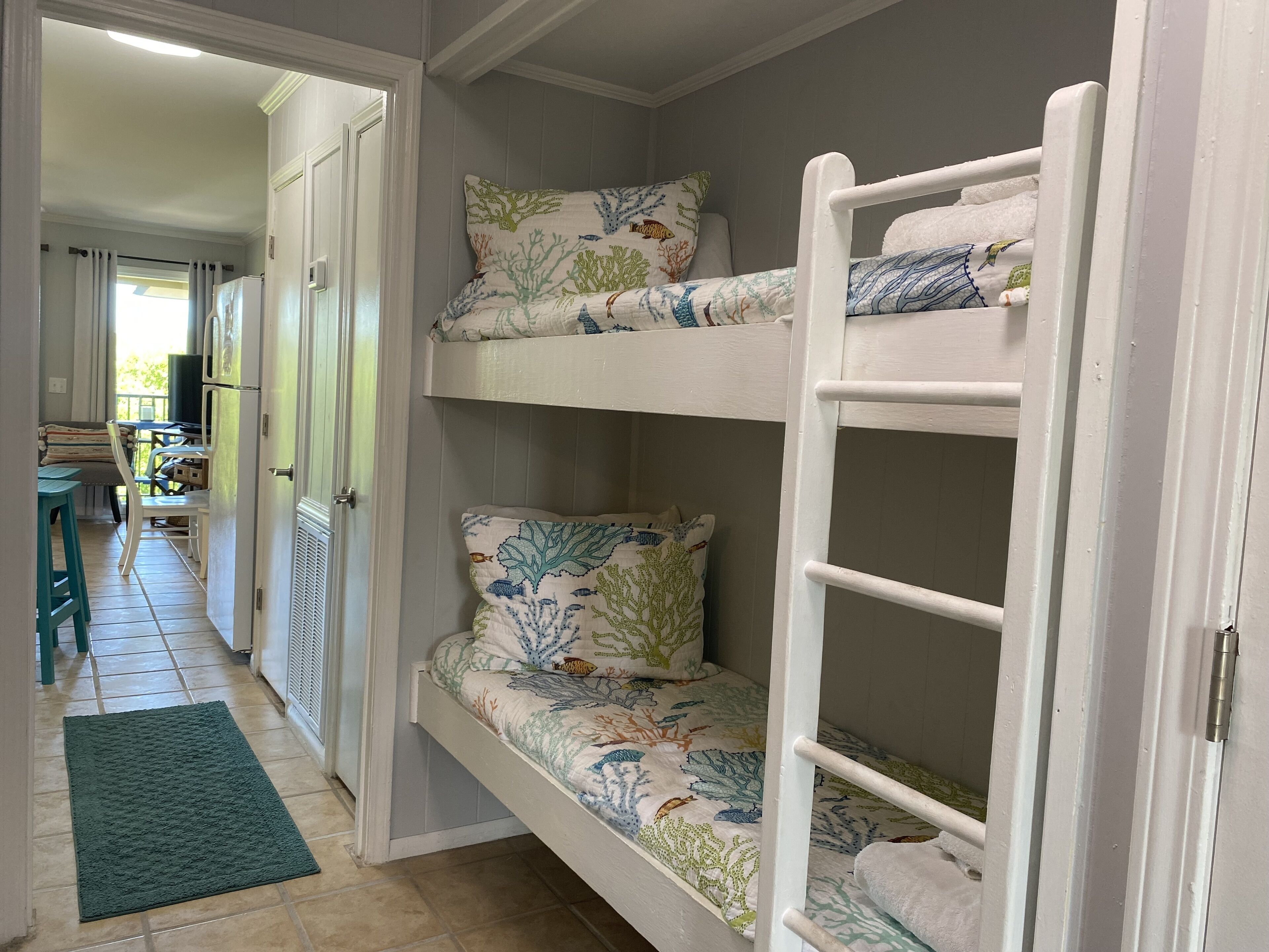 A bunk bed with floral bedding and a green mat in a hallway.