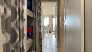 Un pasillo con una cama, una cortina estampada y una puerta que da a un balcón.
