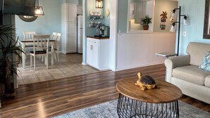 A living room with a wooden coffee table, a sofa, and a dining area with chairs and a table. - Ocean View - Admiral's Row 231-Professionally Managed by HHIB&T Vacation Rentals (Hilton Head Island)