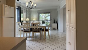 Une cuisine spacieuse avec des meubles blancs, un coin repas comprenant une table et des chaises, et une grande fenêtre offrant une vue sur l’extérieur.