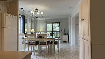Una cocina amplia con armarios blancos, un comedor con mesa y sillas, y un ventanal que ofrece vistas al exterior.