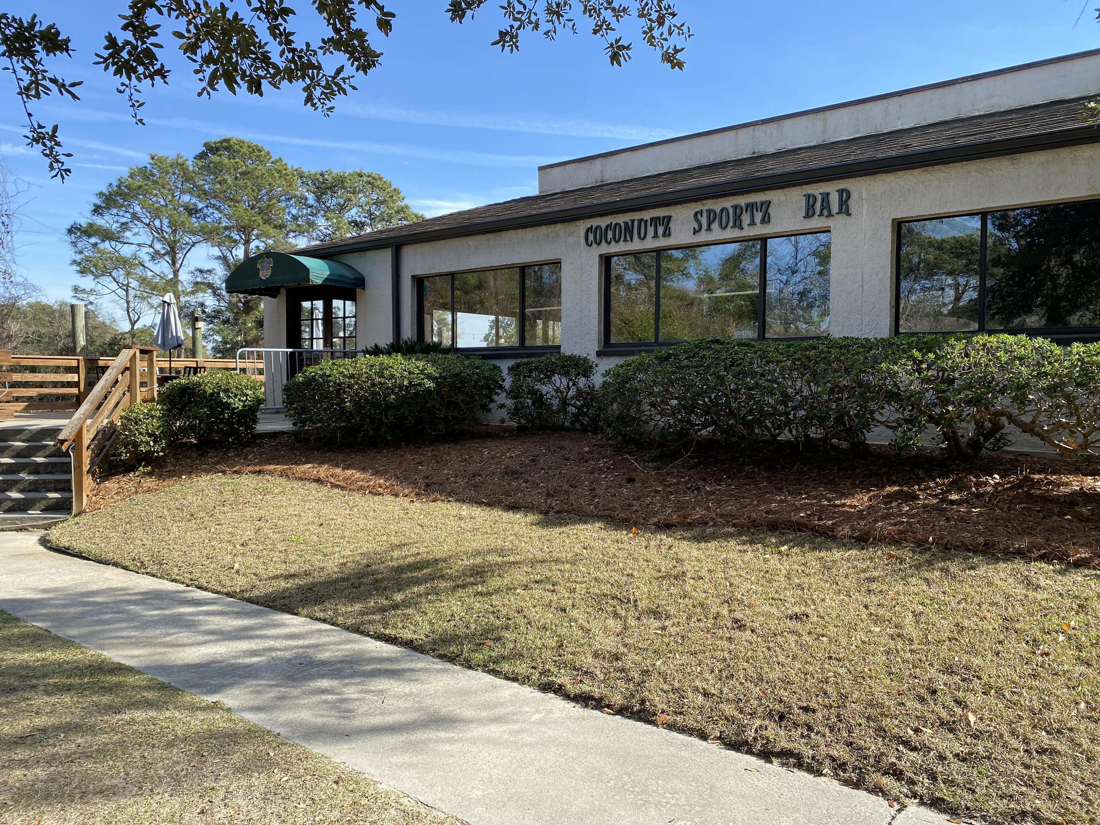 A building with a sign reading 'Coconutz Sportz Bar' and a covered outdoor seating area.