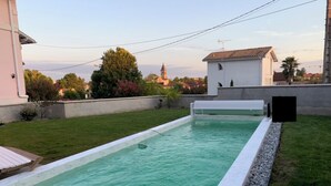 A rectangular swimming pool with a white edge, surrounded by a grassy area and a low stone wall. - Town house near the ocean (20min) (Dax)