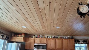 A kitchen with wooden cabinets, a stainless steel refrigerator, and a clock on the wall.