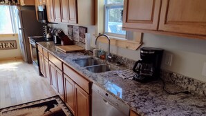 A kitchen with wooden cabinets, granite countertops, stainless steel appliances, and a dishwasher.