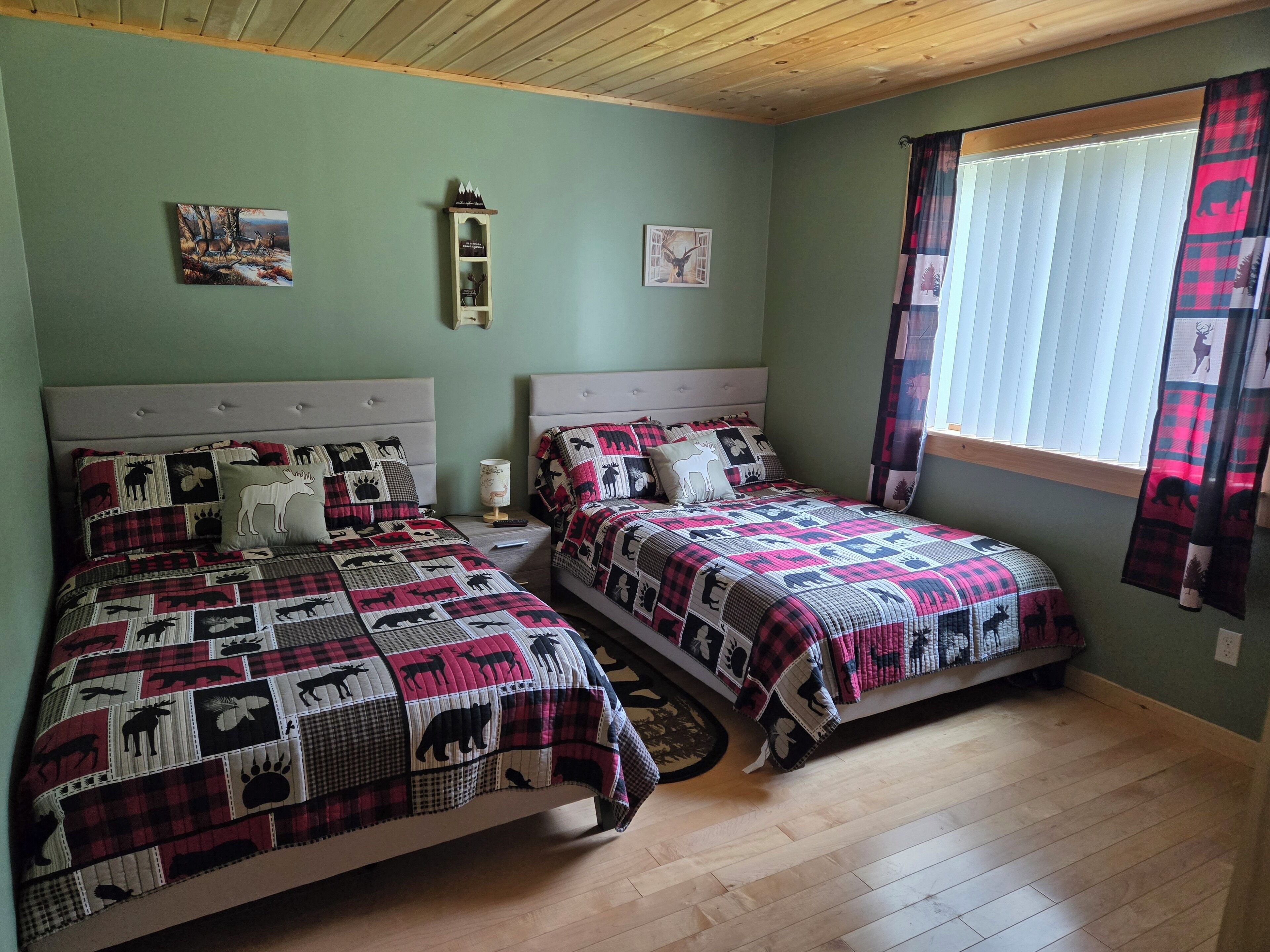 Quarto com duas camas, cada uma com colcha estampada, mesa de cabeceira com abajur e prateleira na parede.