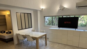 A modern living room with a dining area, a flat-screen TV, and a view through the window. - Chambres D'hôtes Terra Bella (Lecci)