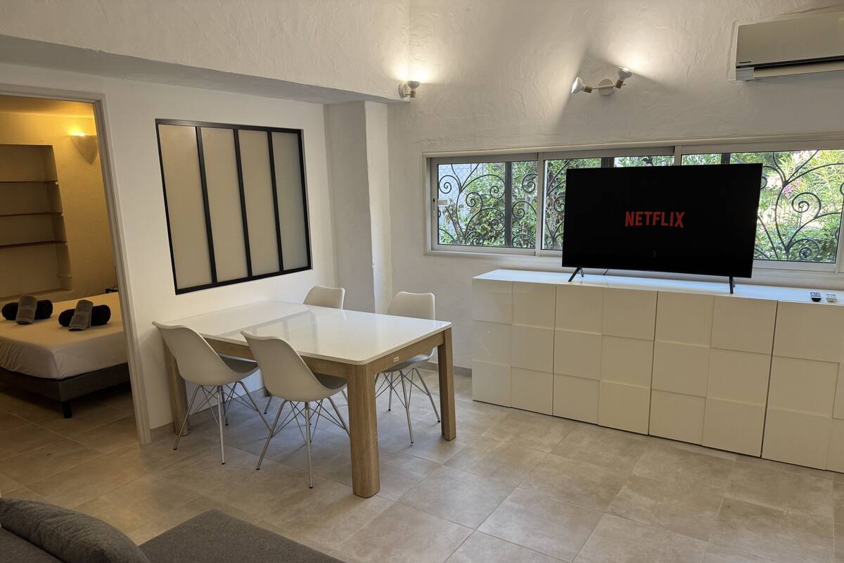 Una sala de estar moderna con comedor, televisor de pantalla plana y vistas al exterior.