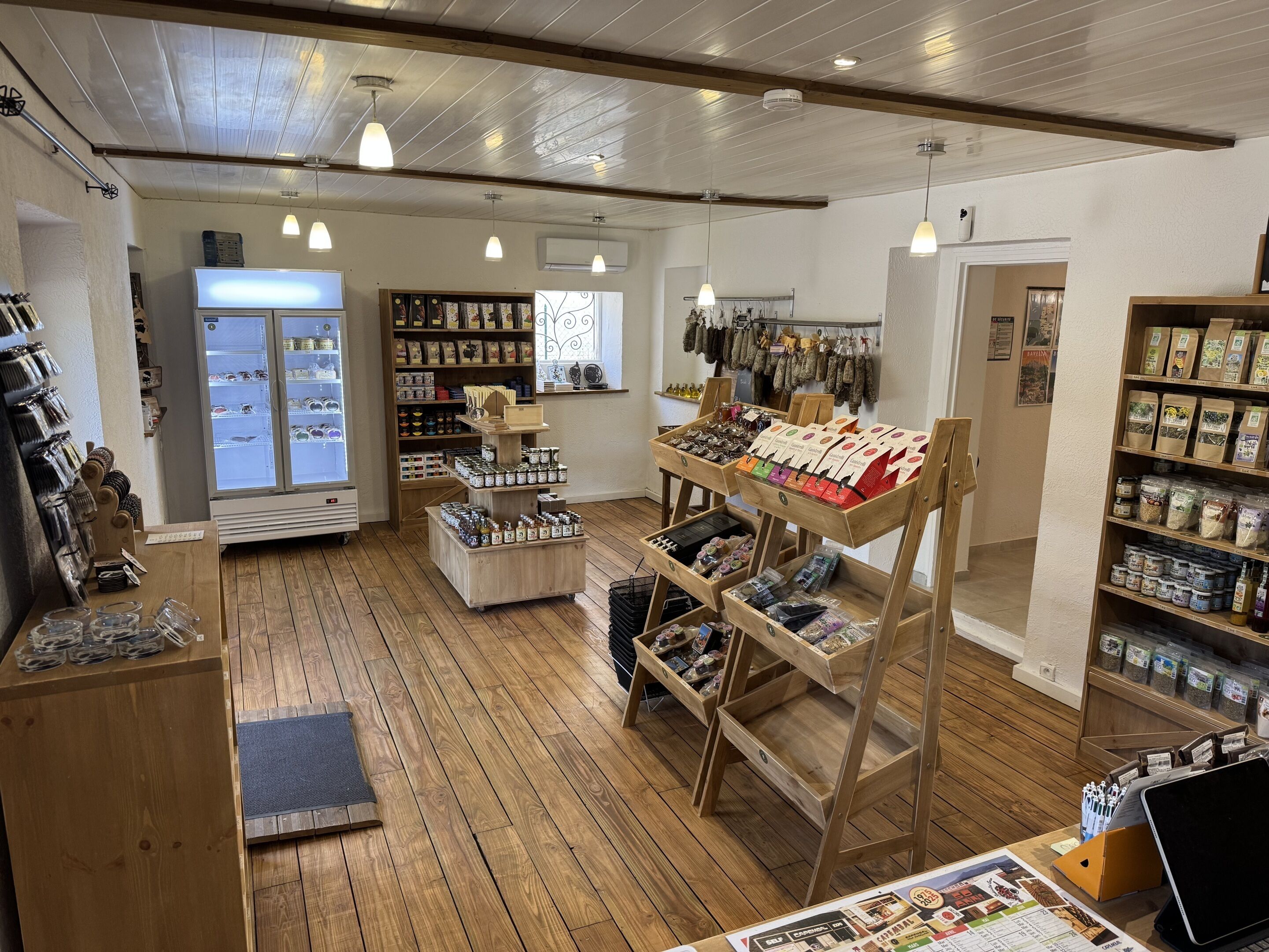 A store interior with wooden floors, shelves stocked with products, and a display counter.