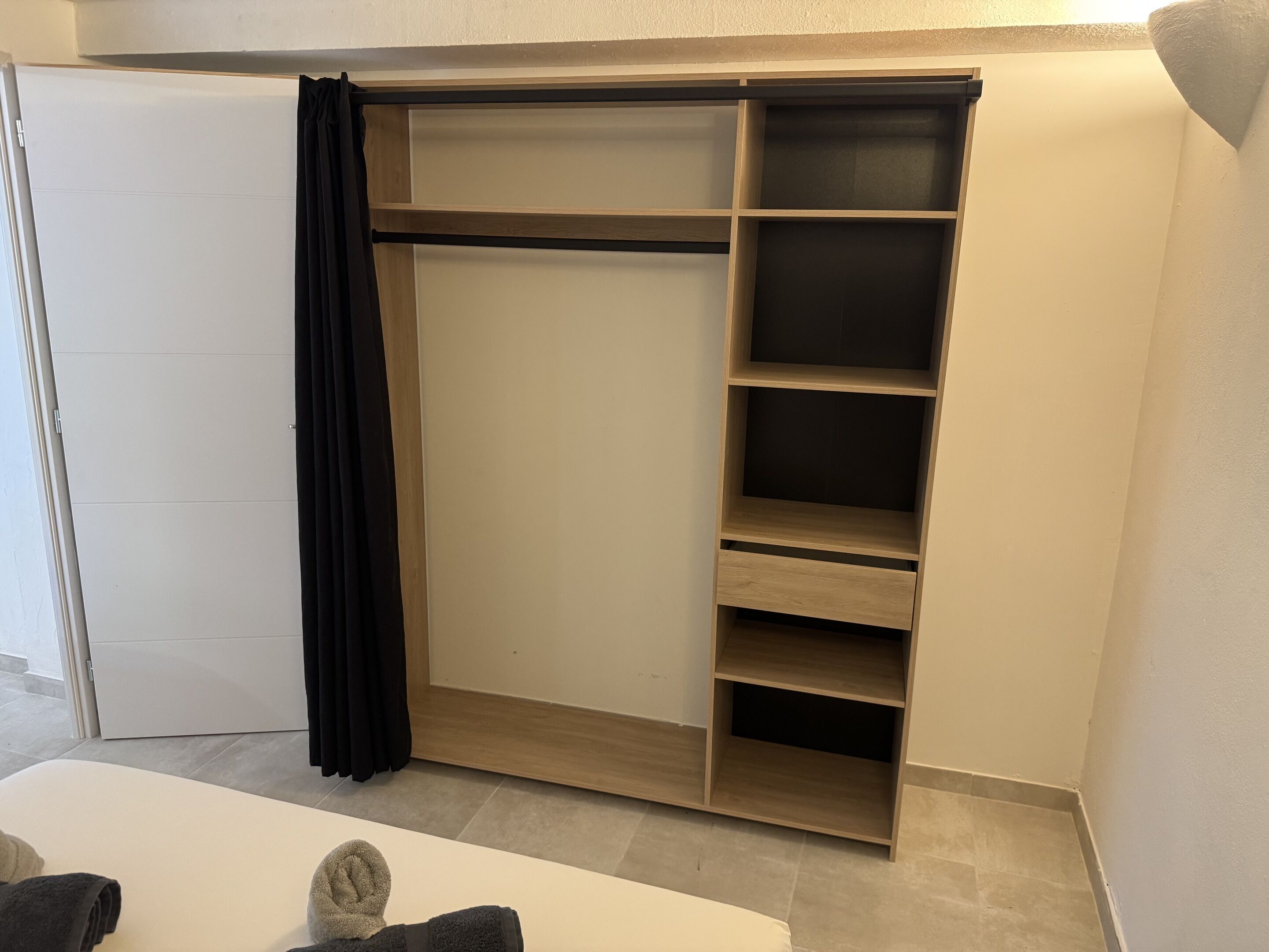 Un vestidor con puerta corredera, varios estantes y una barra para colgar ropa.