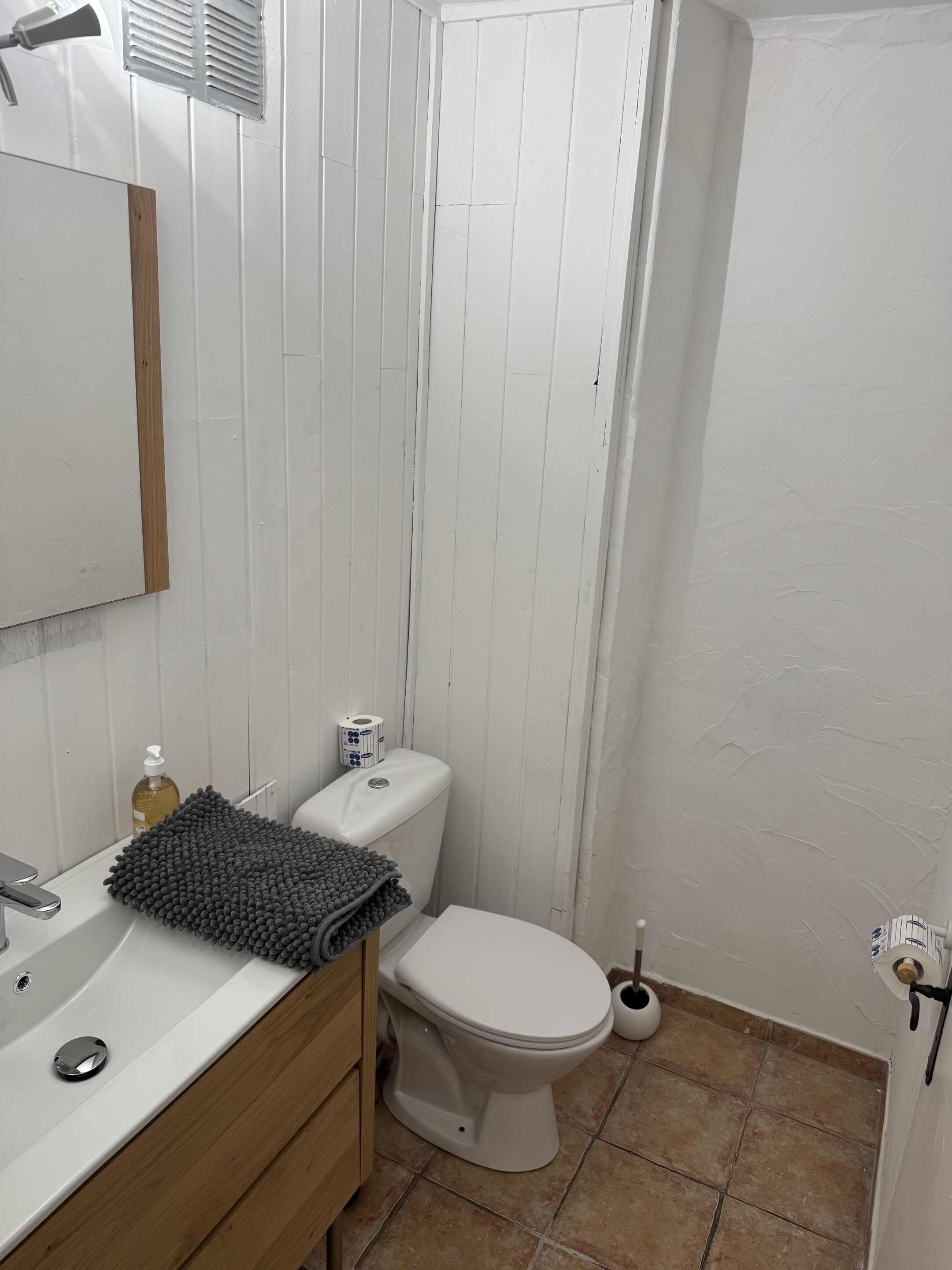 Ein Badezimmer mit weißem Waschbecken, Spiegel, Toilette und Duschbereich.