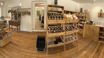 A store with wooden flooring, shelves with various products, and a refrigerator.